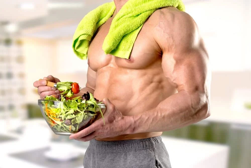 Powerful athletic man with great physique eating a healthy salad.