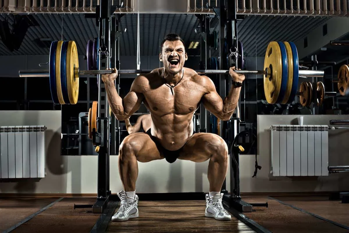 bodybuilder squating with olympic weights